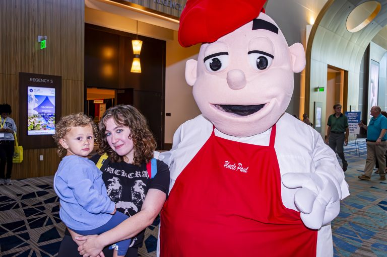 The Family Cafe mascot with two attendees at the conference.