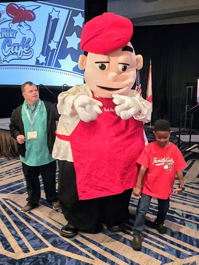 The Family Cafe mascot with a man in a green shirt and a boy in a red Family Cafe shirt