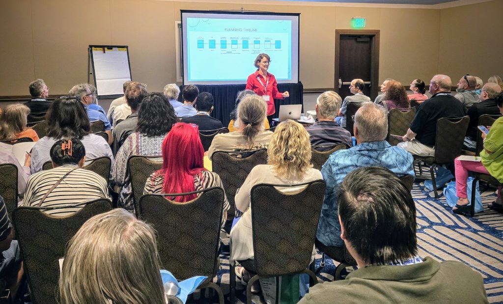 Person in front of a screen delivering a presentation to an audience